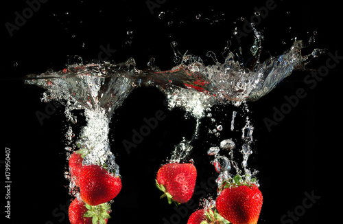 Strawberries splashing into water