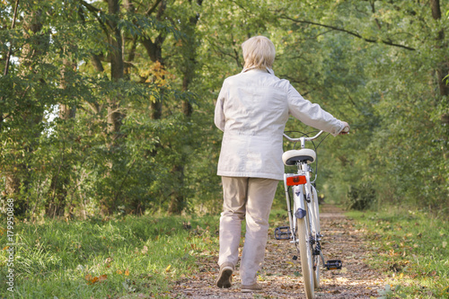 Active happy carefree smiling senior woman ridding bike in autumn nature.