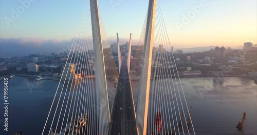 Statatic aerial view of the Zolotoy Bridge (the Golden Bridge, built in 2012) and cars driving across it. It's cable-stayed bridge across the Zolotoy Rog harbour. Vladivostok, Russia. Autumn sunrise photo