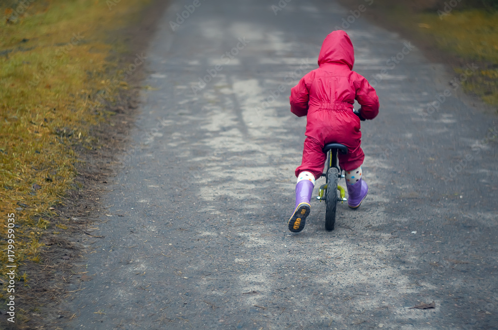 Obraz premium cute little girl riding run bike in the forest