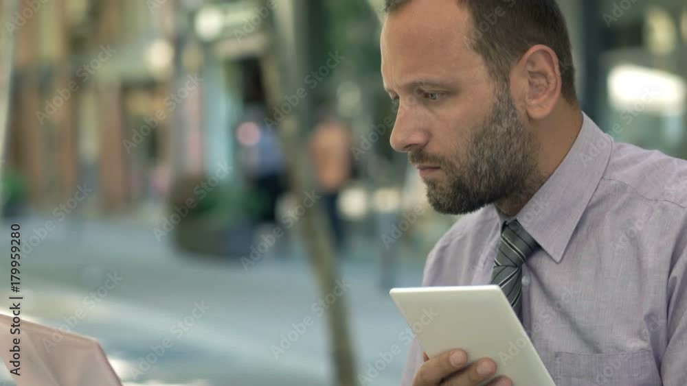 Businessman working with tablet and laptop sitting in cafe in city
Businessman working with tablet and laptop sitting in cafe in city