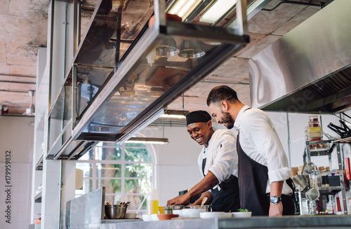 Two cooks preparing food in restaurant kitchen photo