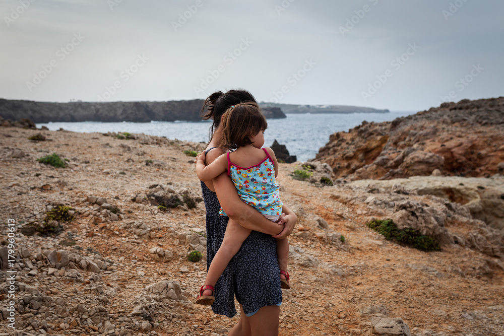 Madre e hija mirando al mar en un acantilado