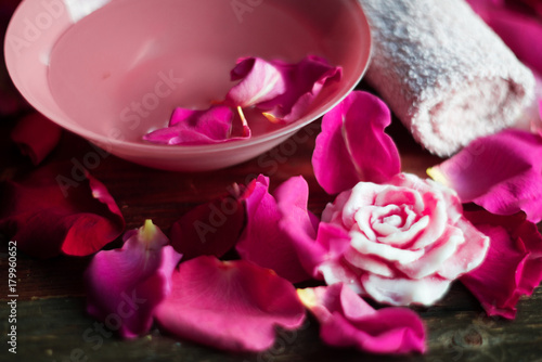 Bowl with water and rose petals on wooden table