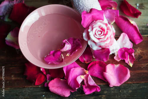 Bowl with water and rose petals on wooden table