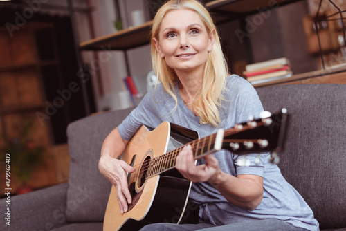 middle aged woman with guitar at home