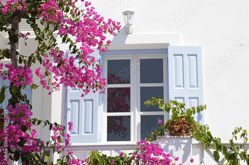 Window with blue wooden shutters in a white whitewashed facade, Oia, Santorini, Greece photo