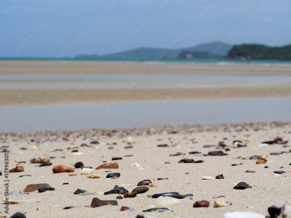 Colorful gravel on the sand, blurred background beach and sea.