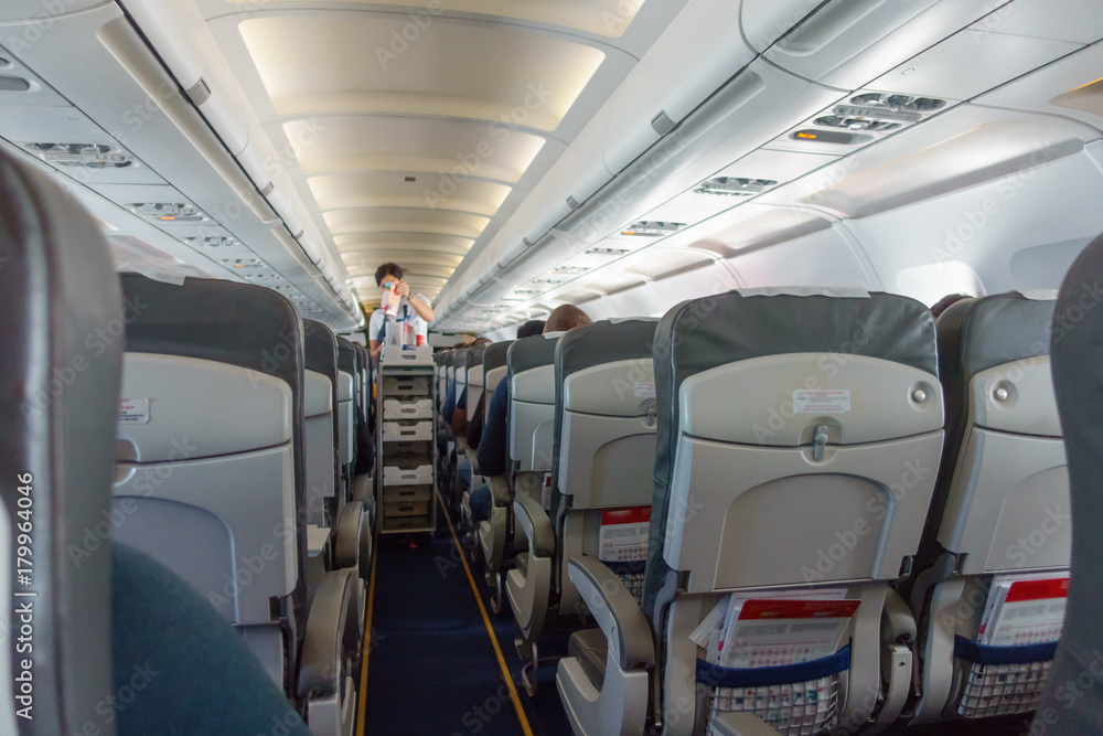 Obraz premium Stewardess offers food and drinks to economy class passengers on the plane