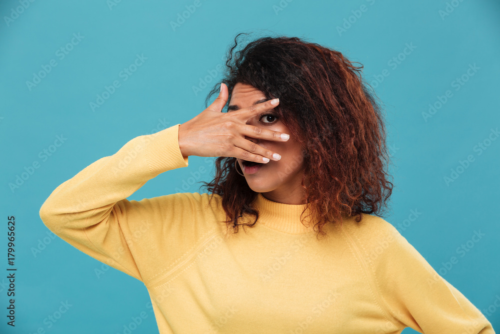 Young lady dressed in warm sweater covering face with hands. Young lady dressed in warm sweater covering face with hands.