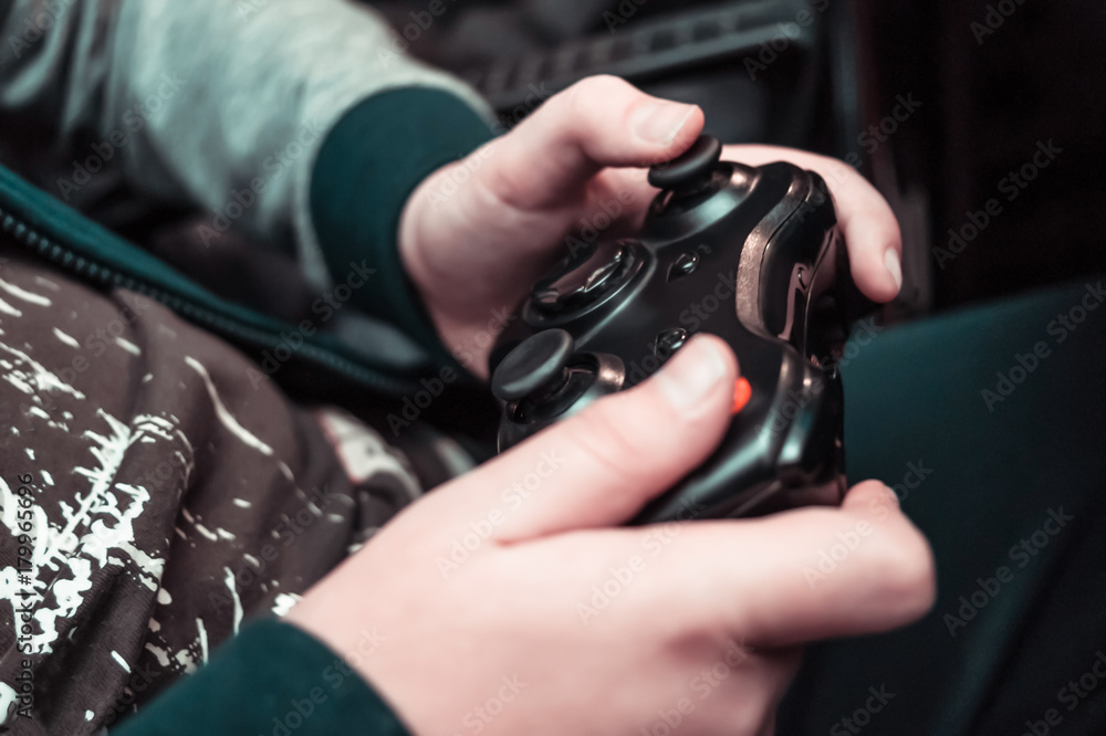 Entertainment, home electronics, gaming concept: a teenager hands holding wireless controller gamepad playing console video game