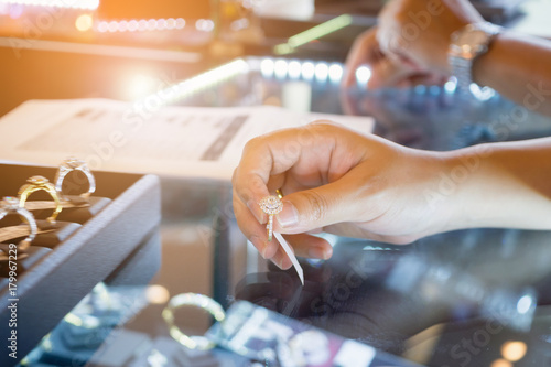 Slika na platnu Asian woman choosing wedding rings at jewelry diamond shop