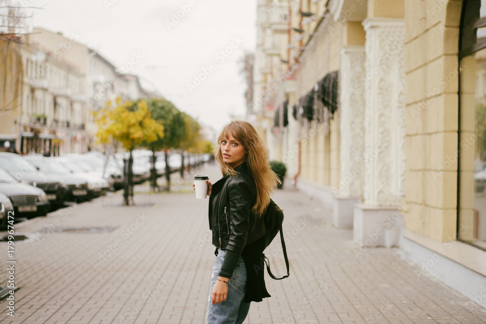 Portrait of a beautiful girl on the street, holding a paper cup