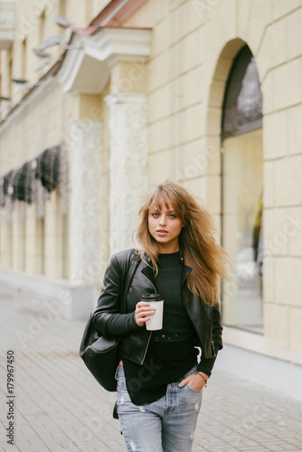 Portrait of a beautiful girl on the street, holding a paper cup