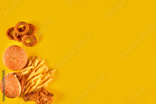 Fast food dish on yellow background. Fast food set fried chicken, meat burger and french fries. Take away fast food. © nazarovsergey