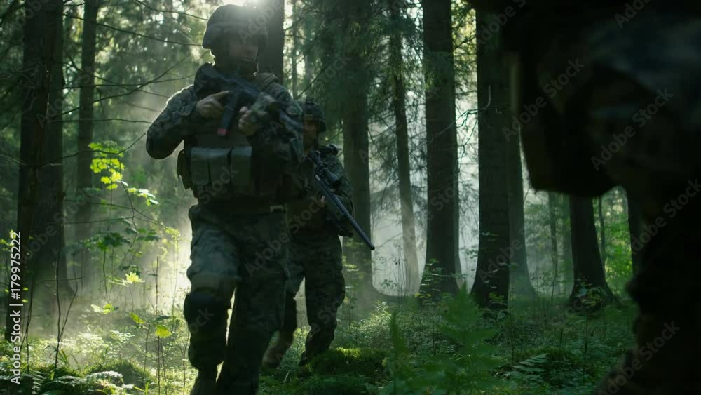 Squad of Five Fully Equipped Soldiers in Camouflage on a Reconnaissance Military Mission, Rifles Ready to Shoot. They're Moving in Formation Through Dense Smokey Forest. Squad of Five Fully Equipped Soldiers in Camouflage on a Reconnaissance Military Mission, Rifles Ready to Shoot. They're Moving in Formation Through Dense Smokey Forest.