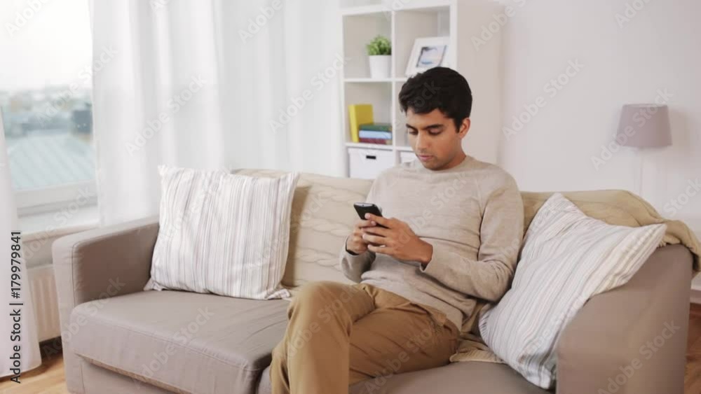 man with smartphone sitting on sofa at home man with smartphone sitting on sofa at home