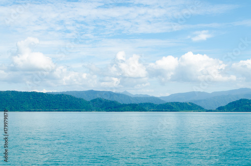 Horizontal of Seascape including Forest Mountain  Blue Sky and Wave of Water Foam in Ocean.