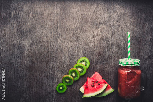 Watermelon fresh smoothie in glass jar, slices of watermelon on a dark wooden background