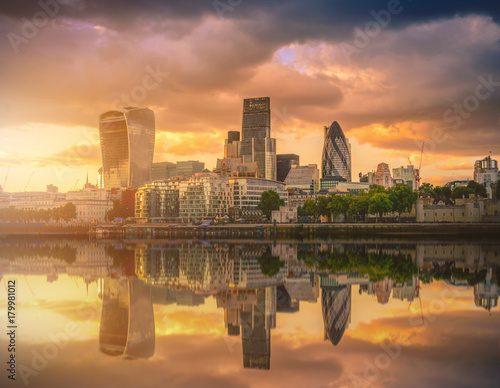 Skyscrapers of the City of London over the Thames river at sunset in England.