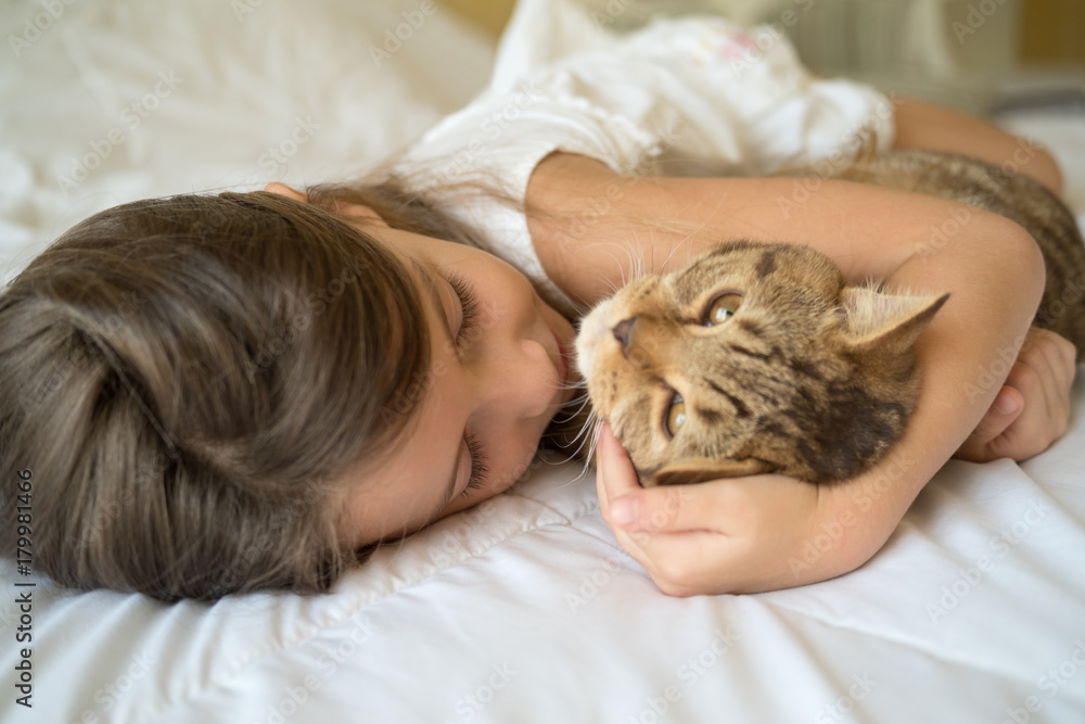 Child playing with cat on bed Child playing with cat on bed