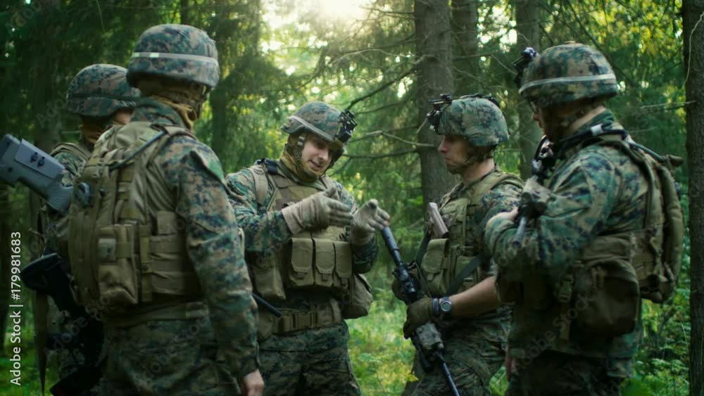 Squad Leader Discusses Military Operation Details with Soldiers, Commander Gives Orders. Fully Equipped and Armed Soldiers Ready for Mission in a Dense Forest. Squad Leader Discusses Military Operation Details with Soldiers, Commander Gives Orders. Fully Equipped and Armed Soldiers Ready for Mission in a Dense Forest.