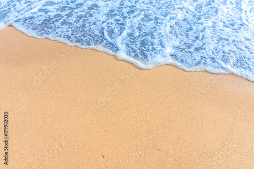 Soft wave with blue ocean on sandy beach.