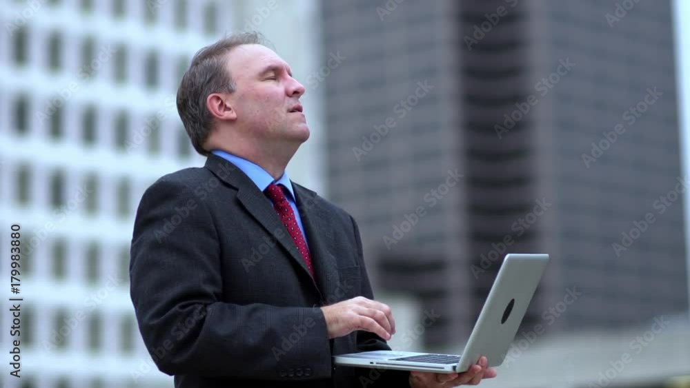 Tired businessman working on laptop outdoors Tired businessman working on laptop outdoors