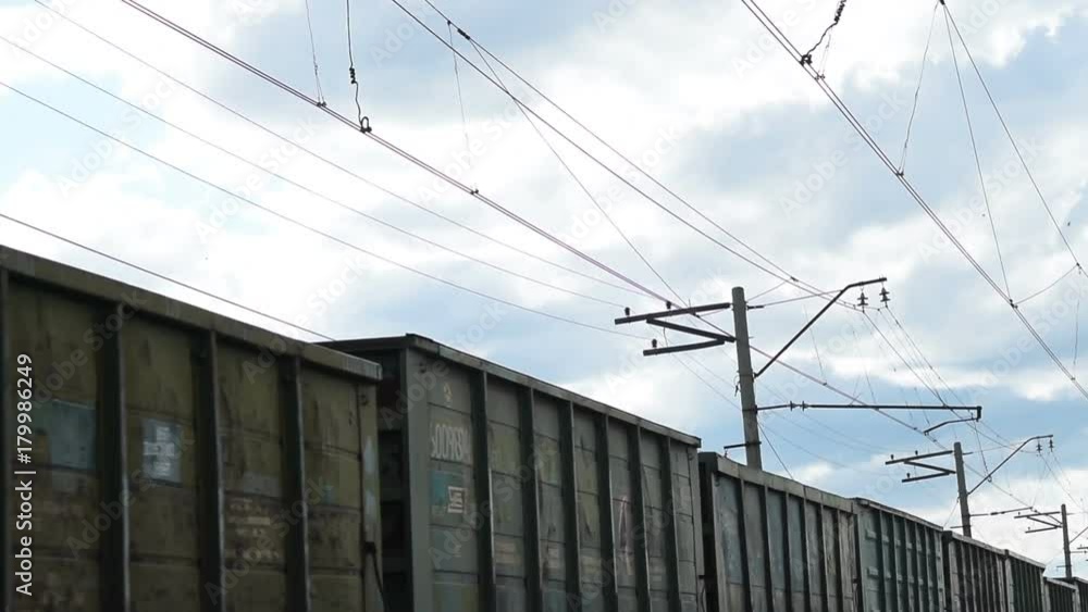 Moving cargo train, power line and cloudy sky. Railway freight traffic Moving cargo train, power line and cloudy sky. Railway freight traffic
