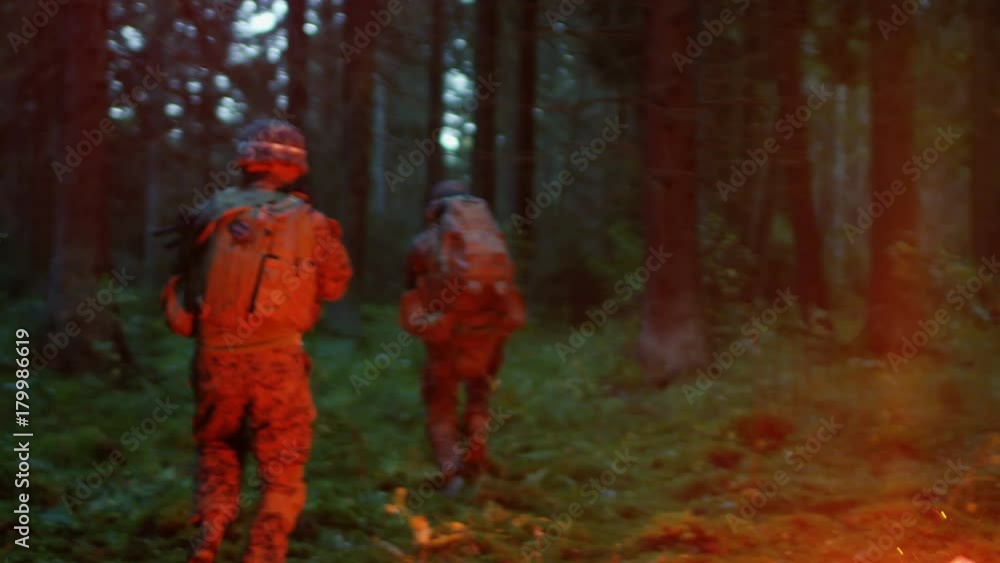 Squad of Five Fully Equipped Soldiers in Camouflage on a Reconnaissance Military Night Mission. They're Illuminated by Red Flare and Move Through Dense Forest. Squad of Five Fully Equipped Soldiers in Camouflage on a Reconnaissance Military Night Mission. They're Illuminated by Red Flare and Move Through Dense Forest.