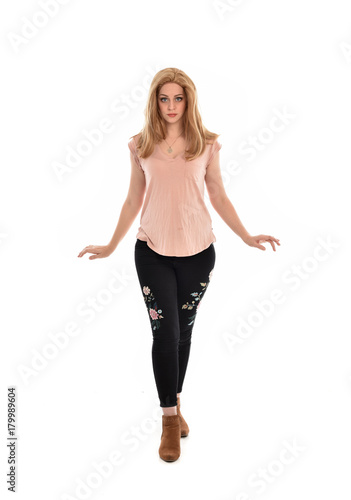 full length portrait of a girl wearing pink shirt and black floral pants. standing pose, isolated on white background.
