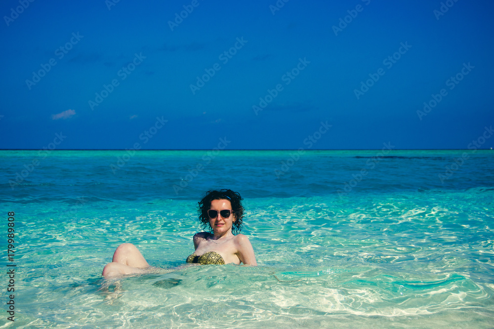 Idyllic paradise island landscape. Exotic tropical beach. Summer vacation, luxury holiday resort, tourism concept. Travel to Maldives. Young woman sunbathing in turquoise crystal clear water.Copyspace Idyllic paradise island landscape. Exotic tropical beach. Summer vacation, luxury holiday resort, tourism concept. Travel to Maldives. Young woman sunbathing in turquoise crystal clear water.Copyspace