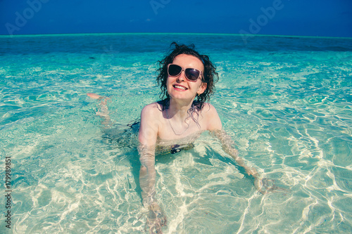Curly hair woman in sunglasses have fun in turquoise crystal clear water. Idyllic paradise island. Exotic tropical beach. Summer vacation, luxury holiday resort, tourism concept. Travel destination.