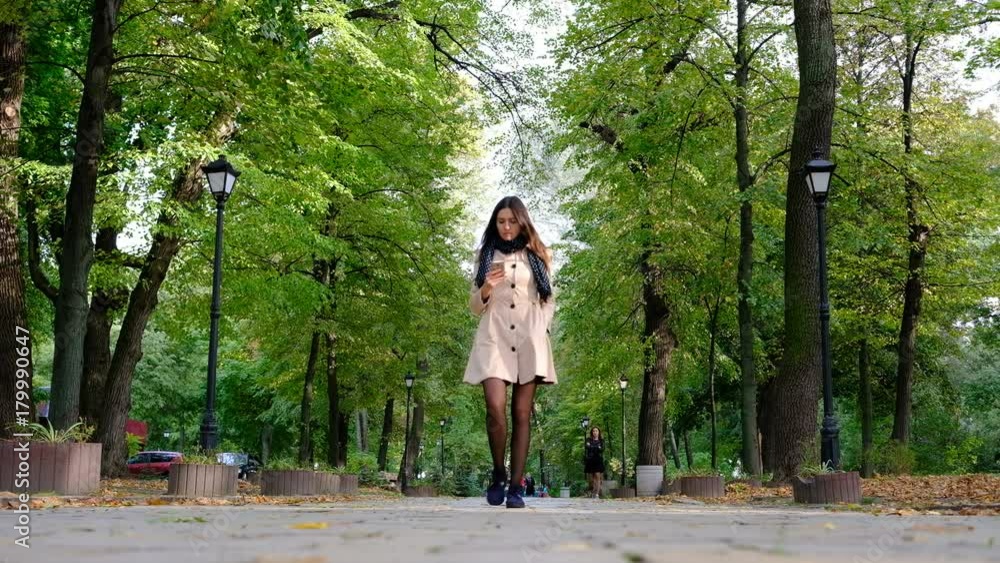 Elegant young woman walking at the autumn park alley Elegant young woman walking at the autumn park alley