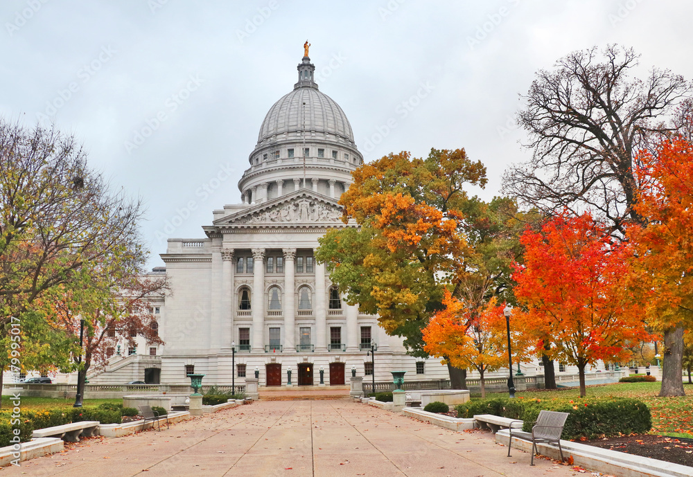 Wisconsin State Capitol building. National Historic Landmark. Madison, Wisconsin, Midwest USA. Autumn view with bright colored trees along path to the entrance and cloudy sky during later afternoon. 