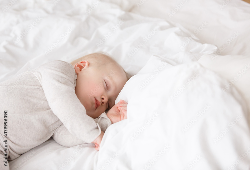 Baby sleeping with open arms and whithout pacifier in a cradle. White pajama and white bed sheets. Baby sleeping with open arms and whithout pacifier in a cradle. White pajama and white bed sheets.