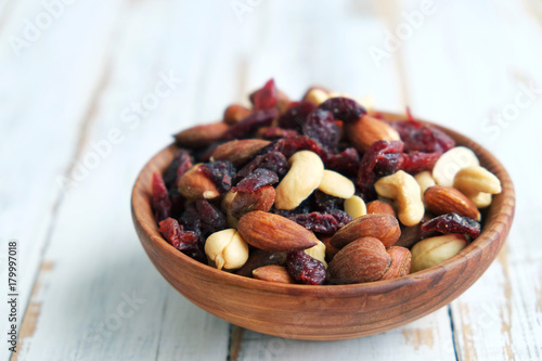 Mixed nuts and dried fruits in a bowl on a white wooden background. 