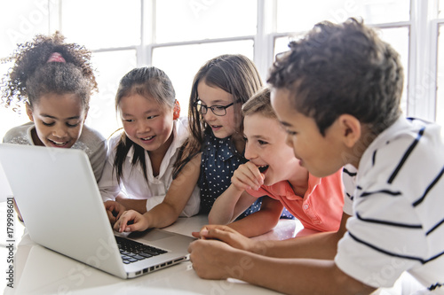 Group of curious children watching stuff on the laptop screen