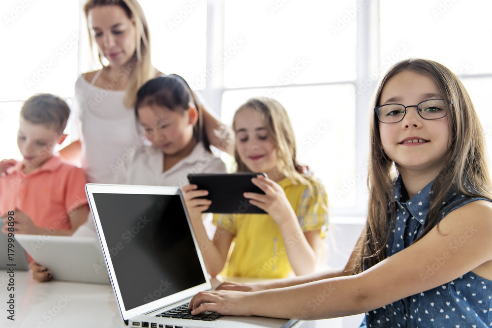 child with technology tablet and laptop computer in classroom teacher on the background child with technology tablet and laptop computer in classroom teacher on the background