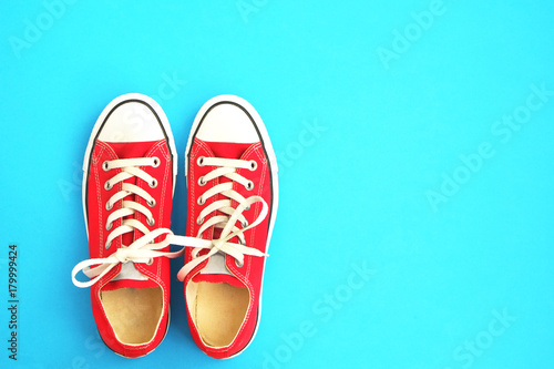 New red sneakers on blue background with copy space. 