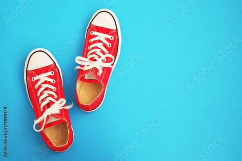 New red sneakers on blue background with copy space. Retro tone. 