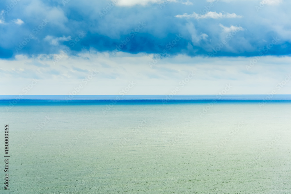 Stylized abstract landscape seascape sunset long exposure with clouds under different shades of blue, orange, yellow and red.