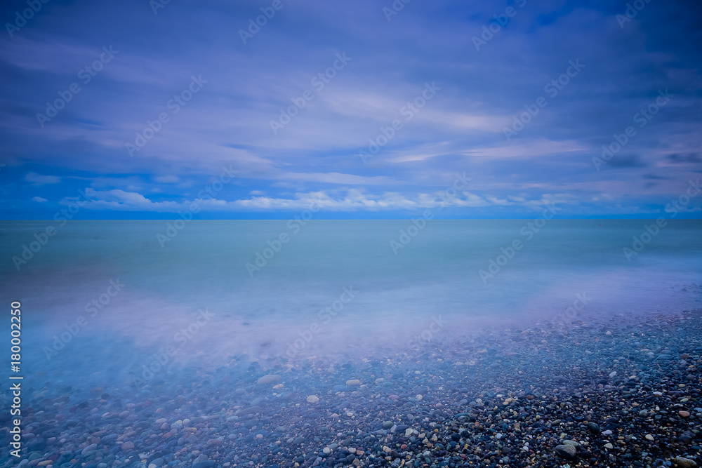 Fototapeta premium Stylized abstract landscape seascape sunset long exposure with clouds under different shades of blue, orange, yellow and red.