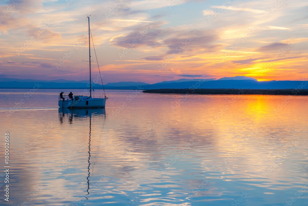 Segelboot treibt in den Sonnenuntergang am Neusiedlersee Segelboot treibt in den Sonnenuntergang am Neusiedlersee