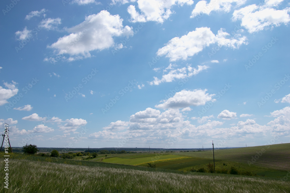 Voluminous white clouds in the blue sky, beautiful summer landscape, fields in the village. Voluminous white clouds in the blue sky, beautiful summer landscape, fields in the village.