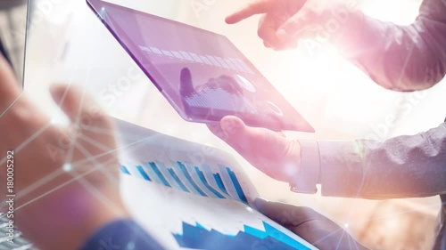 Two colleagues working on global financial strategy using tablet and laptop.Modern business team innovation concept.Office project meeting with virtual graph data interface.4k cinemagraph chart video