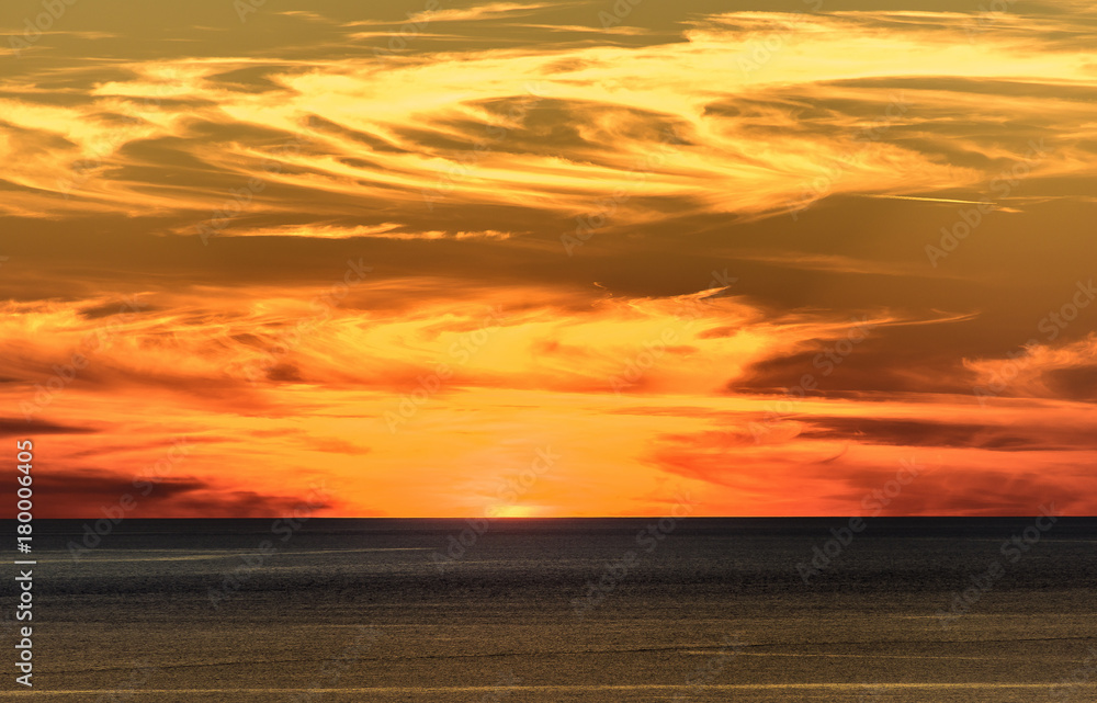 Stylized abstract landscape seascape sunset long exposure with clouds under different shades of blue, orange, yellow and red.