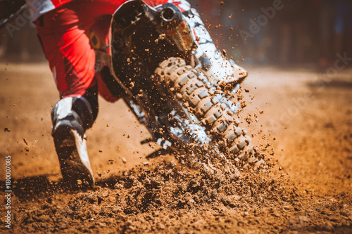 Fototapeta Naklejka Na Ścianę i Meble -  Details of flying debris during an acceleration with mountain bikes race in dirt track in sunshine day time in blurry background. Concept of focus between an accelerate in action sport