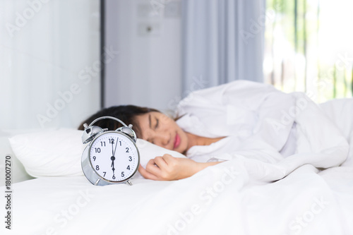 Sleep woman in the morning with alarm clock.