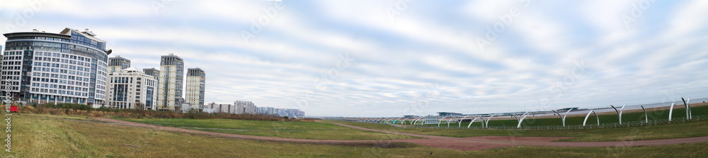 panorama of the city quarter on the coast, green grass, space, morning sky
